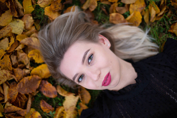 White young european girl in black sweater portrait in autumn foliage - Fotografie, Obrázek