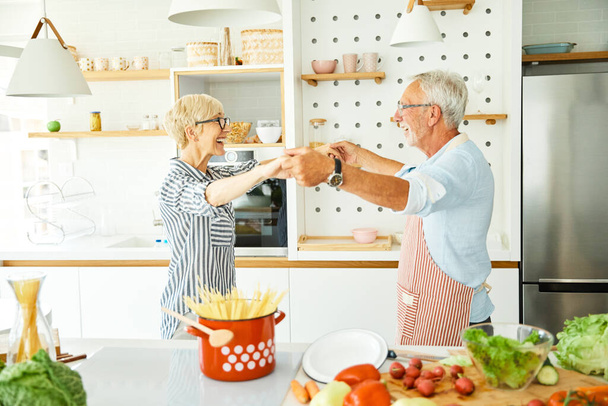 szerelem konyha idősebb nő férfi pár otthon nyugdíj boldog étel mosolygós férj feleség együtt tánc - Fotó, kép