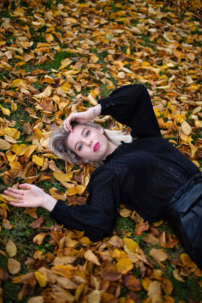 Lying young european white woman with blonde hair in yellow foliage - Fotoğraf, Görsel