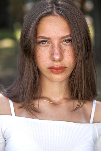 Portrait of a young beautiful brown-haired girl with freckles on her face - Φωτογραφία, εικόνα