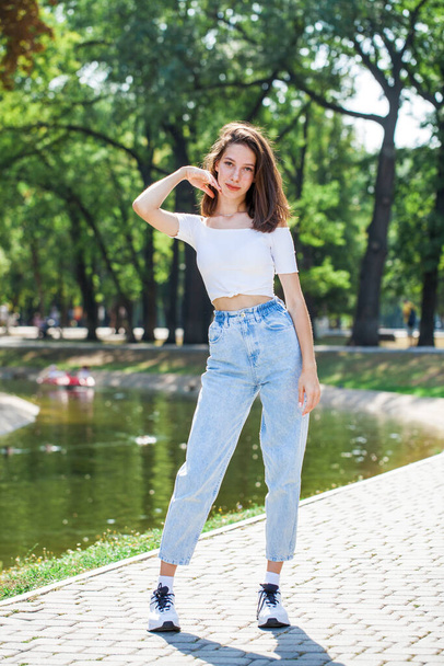 Full length portrait, young beautiful girl in blue jeans posing in a summer park - Foto, Bild