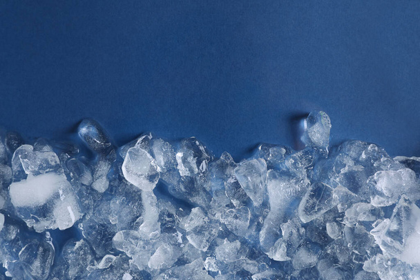 Pile of crushed ice on blue background, top view. Space for text - Foto, afbeelding
