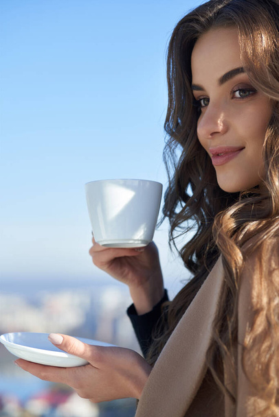 Attractive woman drinking coffee on domestic terrace - Valokuva, kuva