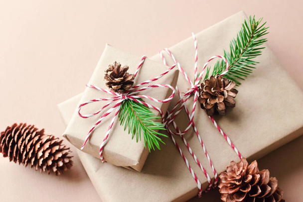 Christmas gift boxes decorated with fir tree twigs and cones on beige background - Valokuva, kuva