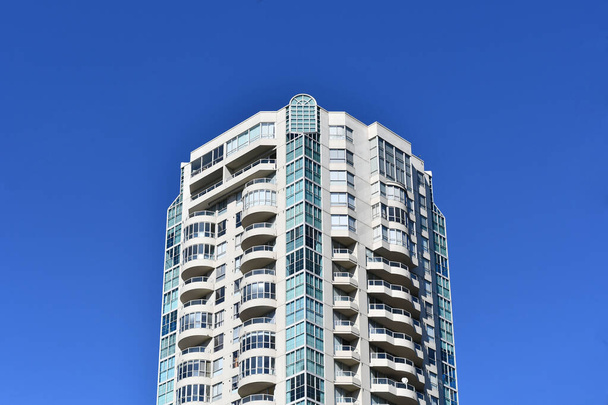 VANCOUVER, CANADA - Jan 06, 2020: A single tall skyscaper building in a blue sky on Robson Street, Downtown Vancouver, Canada - Фото, изображение