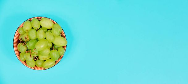 Green table grapes on bowl on blue background. Healthy diet - Фото, зображення