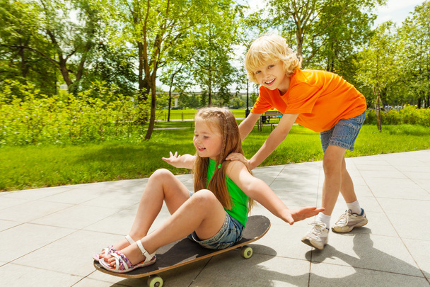 Boy pushes girl on skateboard - Фото, зображення