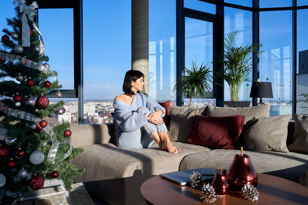 Γοητευτική γυναίκα ξεκουράζεται στο σπίτι με χριστουγεννιάτικη διακόσμηση γύρω - Φωτογραφία, εικόνα