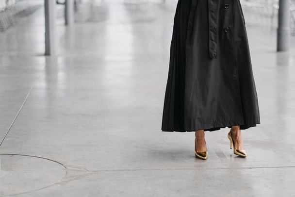 A female in a long black skirt and gold heels in a white room - Photo, Image