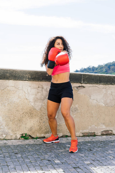 Photo of strong fitness woman boxer in gloves posing outdoors. - Foto, imagen
