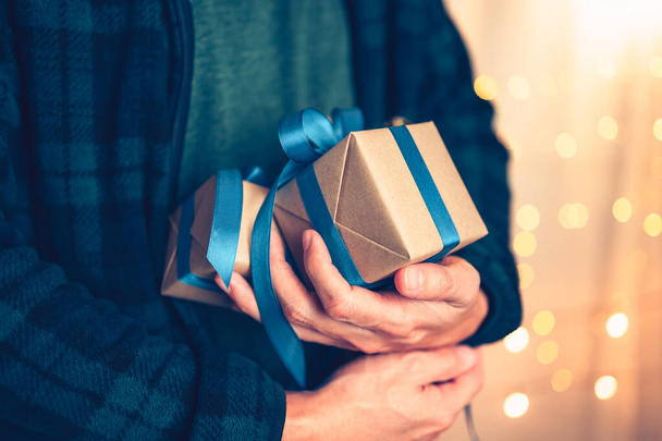 Hands holding gift box, present on the table and light of bokeh background. Valentine's Day, Christmas, Birth day, New year and Anniversary concept. - Fotó, kép