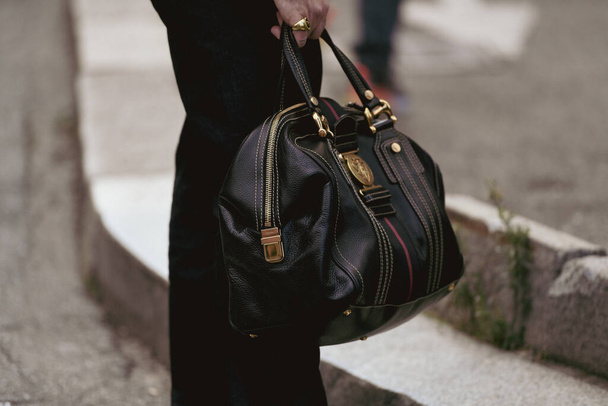 Milan, Italy - September 22, 2021:  Street style outfit, man wearing gray suit pants, a black shiny leather and white visible seams handbag form Gucci on the streets of Milan, Italy. - Фото, изображение