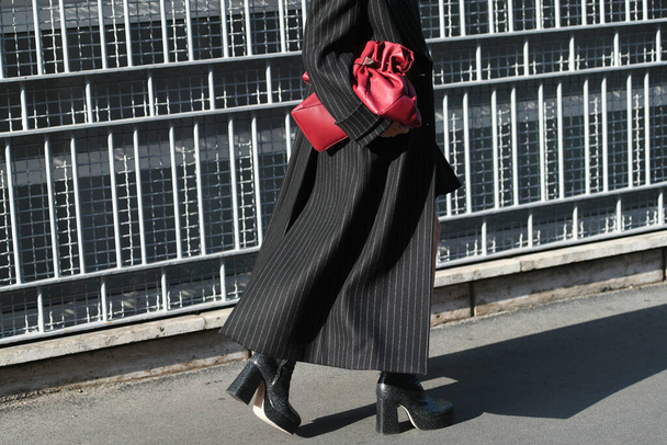 Milan, Italy - September 22, 2021:  Street style outfit, woman wearinga black turtleneck pullover, a black white stripes short skirt, black with white stripes long coat and burgundy shiny leather handbag on the streets of Milan, Italy. - Фото, изображение