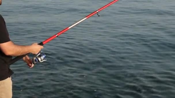 vishengel, man is vissen met een hengel, in de buurt van zee - Video