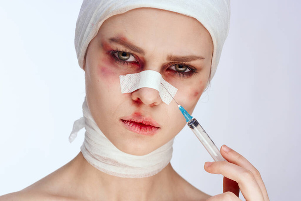 emotional woman with bandaged face bruises syringe in hand painkillers isolated background - Photo, image