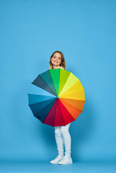 fashionable woman with umbrella rainbow colors posing blue background - 写真・画像