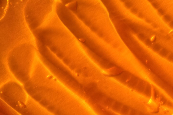 Textura de gel amarillo transparente con burbujas de aire y ondas sobre fondo naranja - Foto, imagen