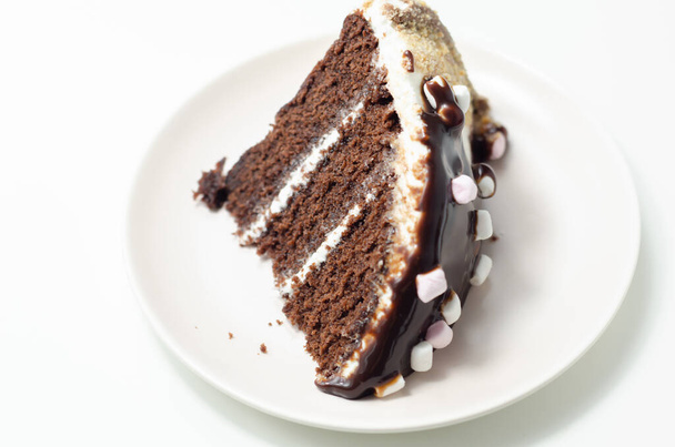 Czekoladowe ciasto biszkoptowe, powleczone i wypełnione lukrem o smaku pianki cukrowej, polewą czekoladową, ozdobione okruchami trawiennymi sosem czekoladowym i piankami, tortem urodzinowym - Zdjęcie, obraz