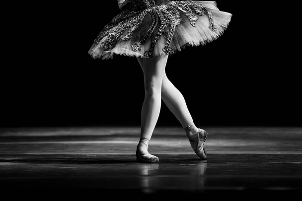 Closeup of ballerina dancing isolated on stage. Ballerina legs closeup - Photo, Image