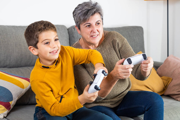 Το μικρό παιδί και η γιαγιά του παίζουν βιντεοπαιχνίδια - Φωτογραφία, εικόνα
