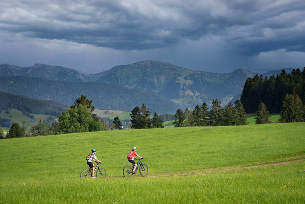 і залишився молодою бабусею з онуком на своїх електричних гірських велосипедах в Альпах Алґеу поблизу Оберстауфена в Баварії (Німеччина). - Фото, зображення