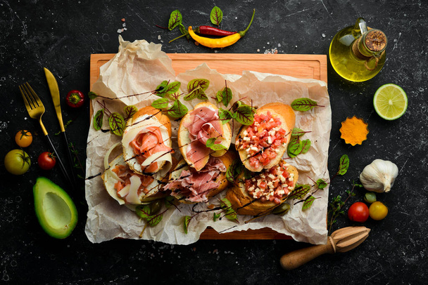Antipasto. Italian food. Bruschetta with prosciutto, cheese and salmon on a wooden board. Top view. Rustic style. - Photo, image
