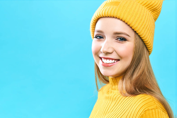 Das Porträt einer jungen Frau, die ihren Einkauf während eines großen Black-Friday-Verkaufs genießt. Lächelndes Mädchen mit gelbem Hut und gelbem Pullover auf blauem Hintergrund. - Foto, Bild