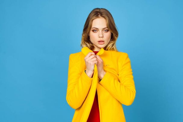 woman in yellow jacket posing makeup fashion blue background - Fotoğraf, Görsel