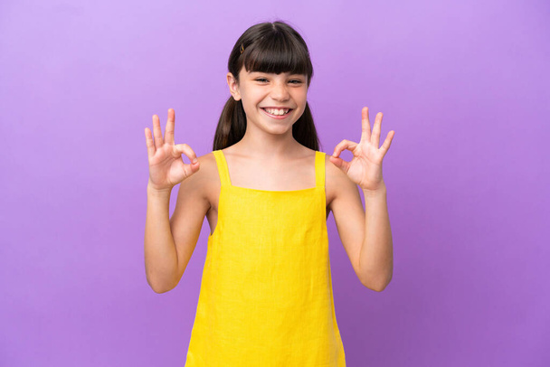 Pequeño niño caucásico aislado sobre fondo púrpura mostrando signo ok con dos manos - Foto, Imagen