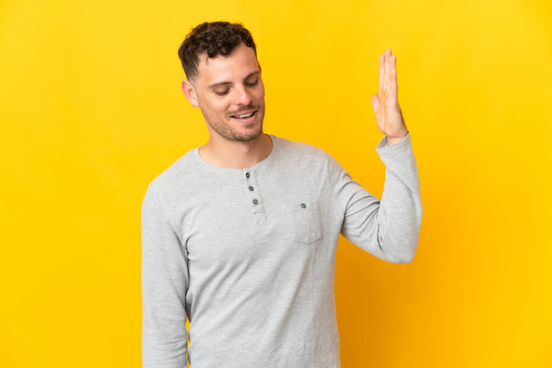 Young caucasian handsome man isolated on yellow background with tired and sick expression - Photo, Image