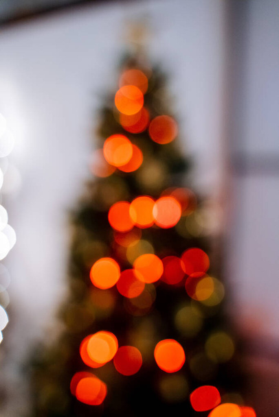 Christmas and New Year. Blurry frame of the Christmas tree. Red glare garland, festive mood. Light highlights. Decorations before the holiday - Foto, Imagem