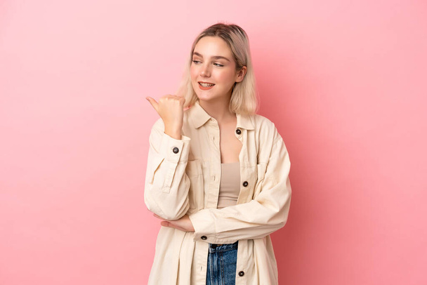 Young caucasian woman isolated on pink background pointing to the side to present a product - Photo, Image