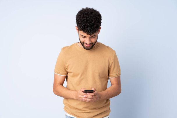 Nuori, sinisellä taustalla eristetty marokkolainen mies lähettää viestin matkapuhelimella - Valokuva, kuva