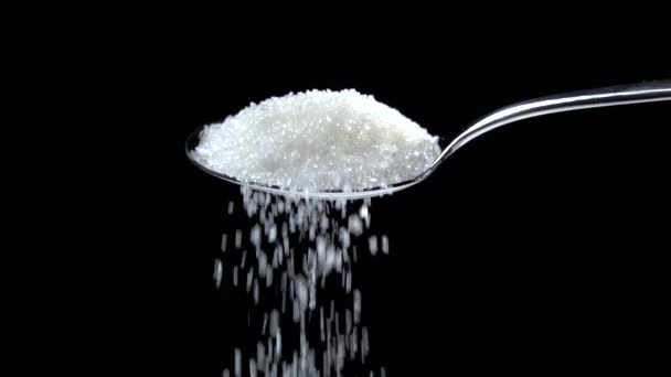 Zucchero che cade dal cucchiaio al rallentatore su sfondo nero - Filmati, video