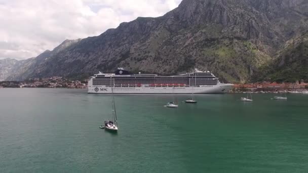 Enorme crucero se encuentra frente a la costa de una antigua ciudad rodeada de montañas - Metraje, vídeo