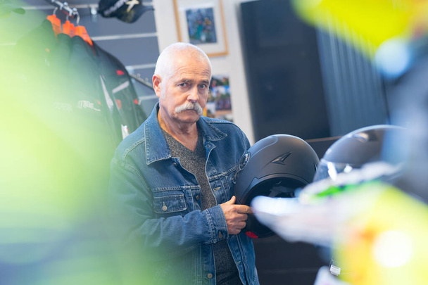 elderly man choosing helmet in store - Fotoğraf, Görsel