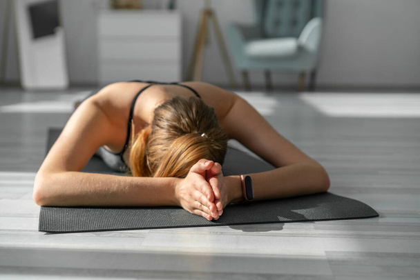 Photo of young concentrated woman doing yoga exercises. Yoga at home. - Foto, afbeelding