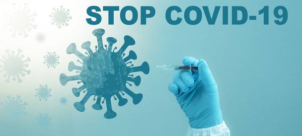 CORONAVIRUS - CORONA VACCINATIE STOP COVID-19 - Arts met spuit in de hand injecteert Corona vaccin in een virus symbool, geïsoleerd op blauwe achtergrond - Foto, afbeelding