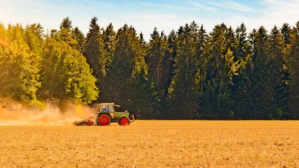 Campagne estivale / agriculture récolte forêt fond bannière panorama : vieux tracteur mouture grain de paille orge champ de blé, avec poussière soufflée, en Forêt-Noire, Allemagne - Photo, image
