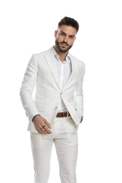 jeune homme d'affaires attrayant tenant une main dans la poche et posant avec style sur fond blanc - Photo, image