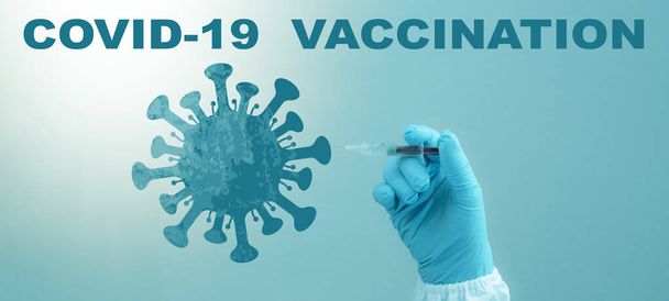 CORONAVIRUS - CORONA VACCINATION STOP COVID-19 - врач со шприцем в руке вводит вакцину Corona в символ вируса, выделенный на синем фоне - Фото, изображение