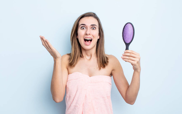 young pretty woman feeling happy and astonished at something unbelievable. hairbrush concept - Fotoğraf, Görsel