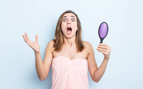 young pretty woman amazed, shocked and astonished with an unbelievable surprise. hairbrush concept - Фото, зображення