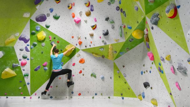 jeune jolie femme sportive grimpe rocher sur le mur de rocher d'escalade dans la salle de rocher d'escalade - fond d'escalade - Photo, image