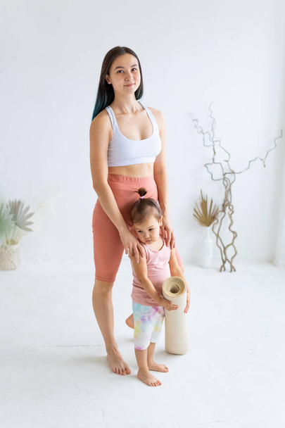 Young mother with little daughter before yoga practice. Full-length portrait.  - Photo, image