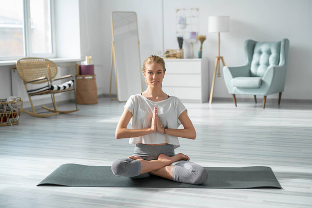 Young woman doing yoga in living room. - Фото, зображення