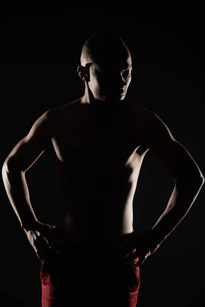 Silhouette of handsome and topless black male posing in his red jeans - Fotó, kép