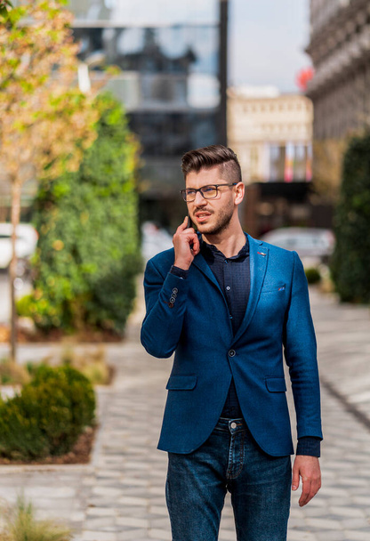 Fashion male businessman with cellphone going in his office - Zdjęcie, obraz