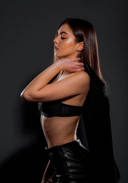 Portrait of a beautiful female model posing in trendy black bra and leather pants - Photo, Image