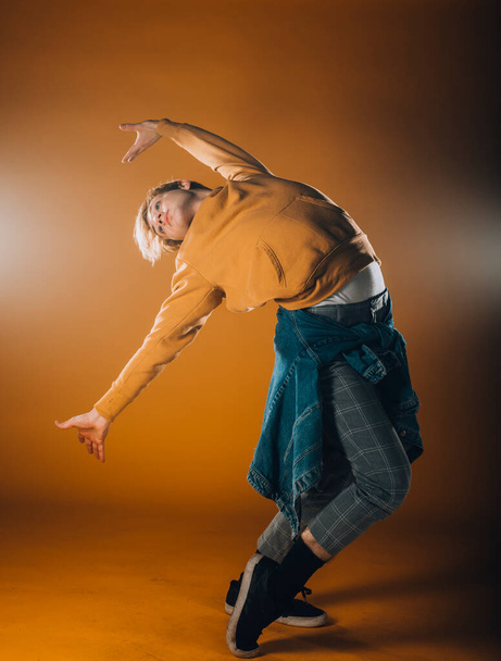 Dançarino masculino muscular executando uma rotina de dança no estúdio laranja - Foto, Imagem